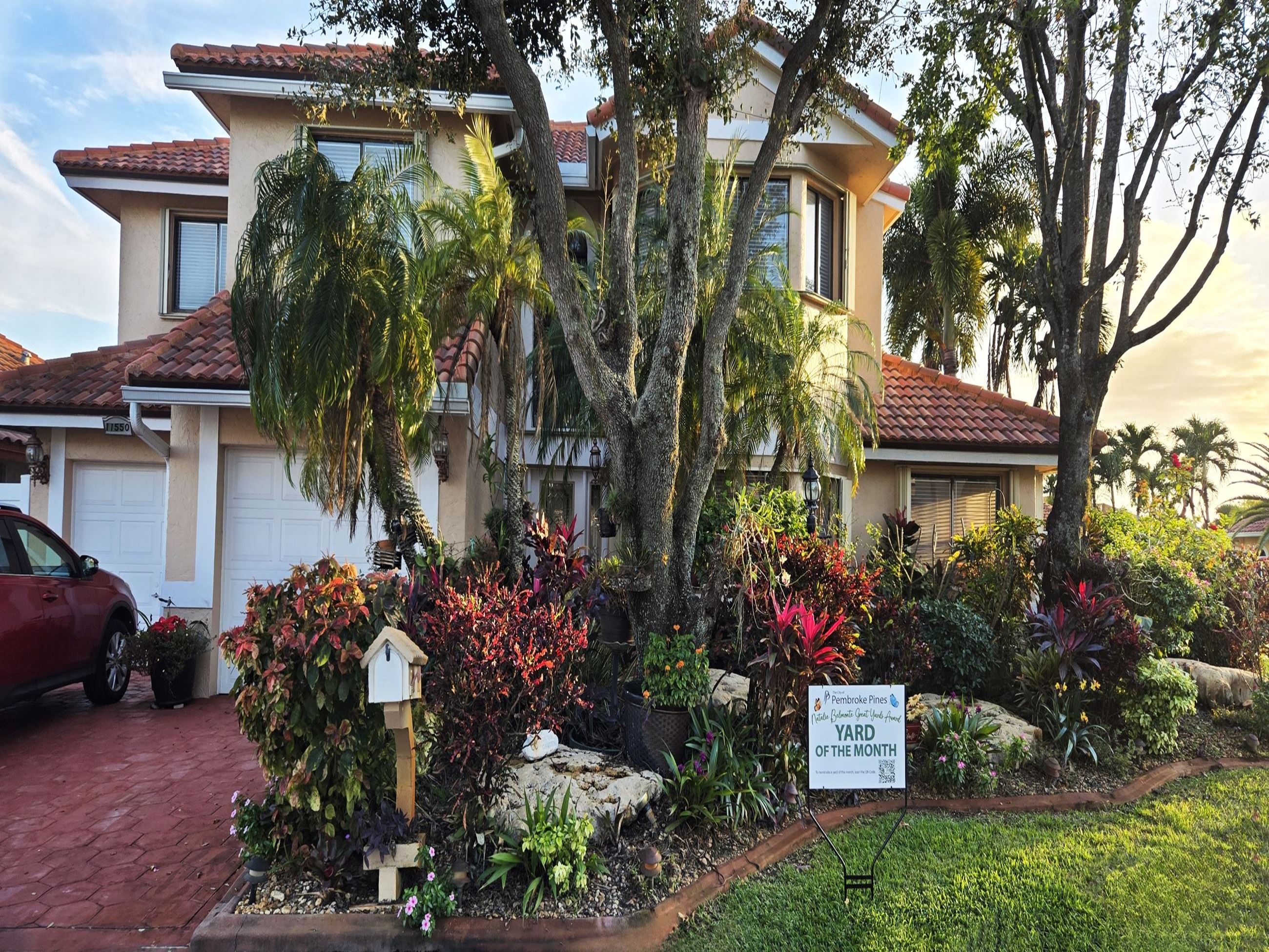 House surrounded by lush greenery and colorful flowers.